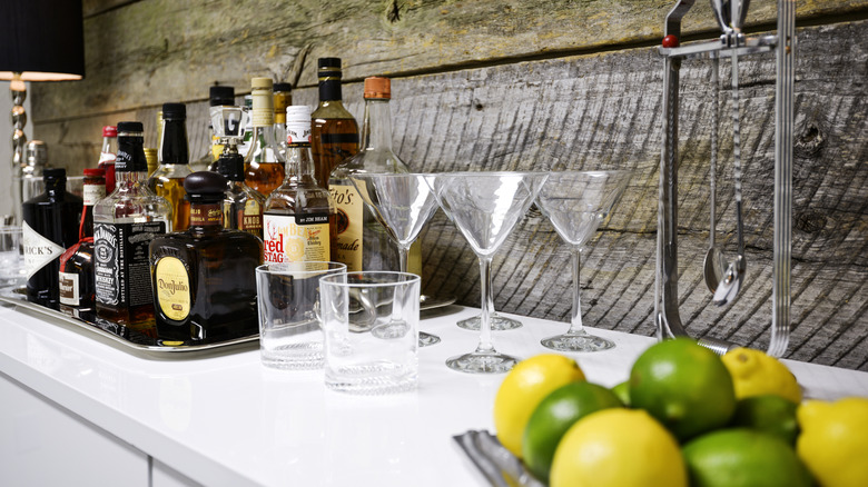 Home bar liquor display with bottles, glasses, lemons, and limes.