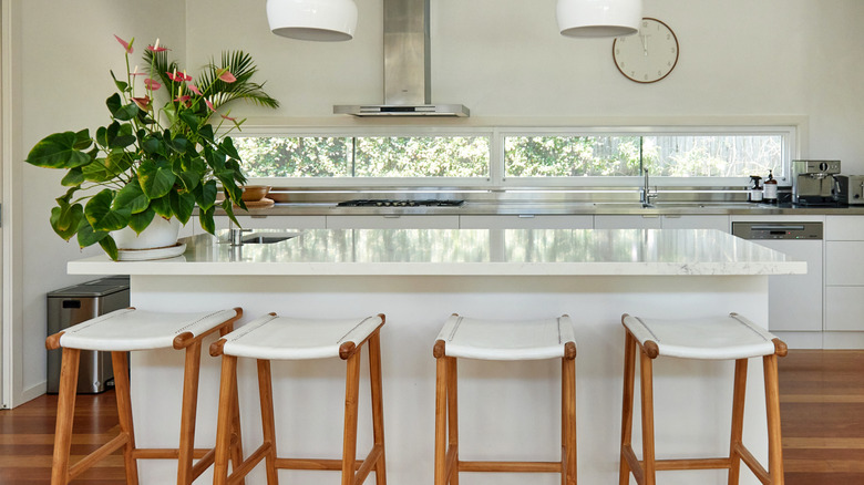 A cozy kitchen with generous natural light, focusing on the kitchen island with four bar stools.