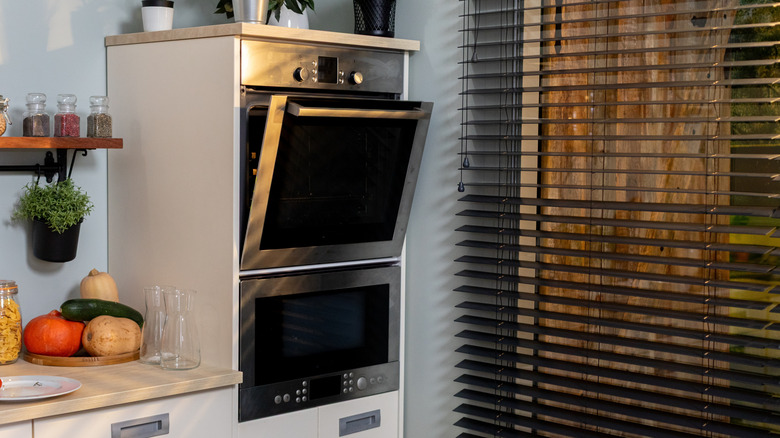 Double oven with top door open near a window in a modern kitchen
