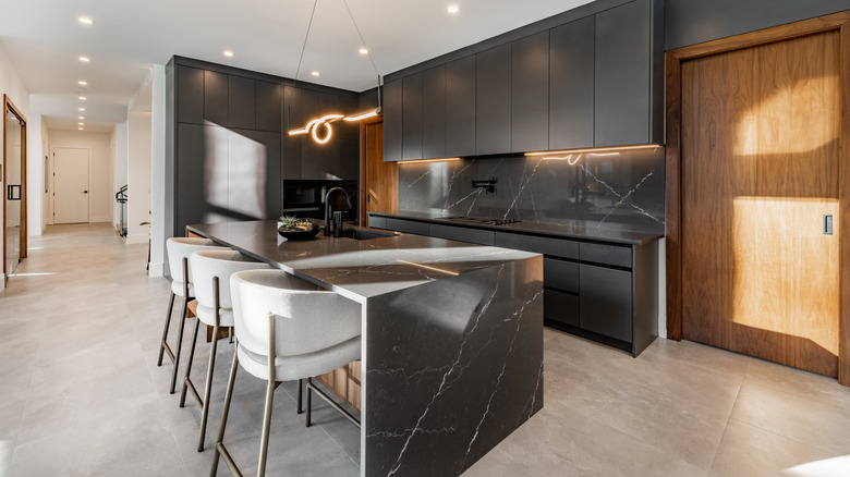dark counters, cabinets, and backsplash in a large kitchen