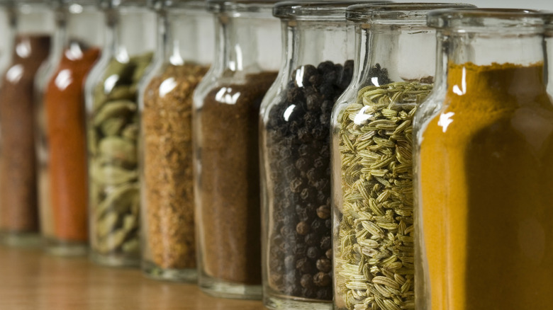 Spices lined up in glass jars in a kitchen