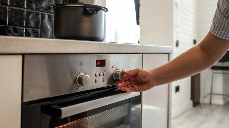hand adjusting the settings knob on an oven in a kitchen