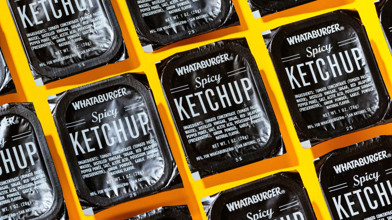Whataburger Spicy Ketchup sauce containers on a yellow background