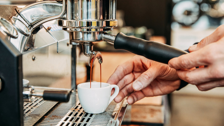 Espresso pouring out of an espresso machine into a small cup
