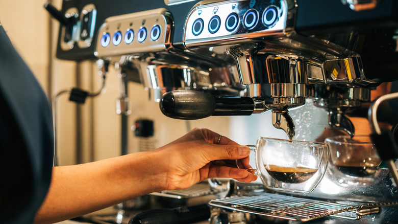 Espresso machine dripping espresso into a small glass cup