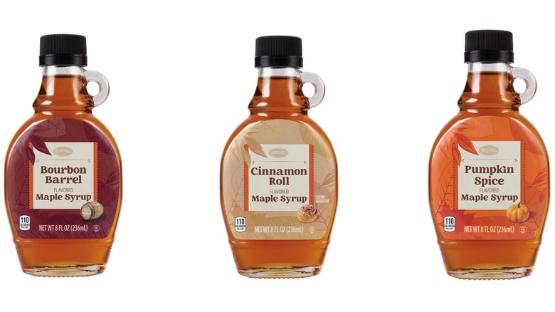 Three clear jars of maple syrup. Bourbon barrel on the left, cinnamon roll in the middle, and pumpkin spice on the right.