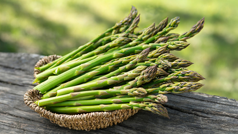 A basket of asparagus on a wooden table.