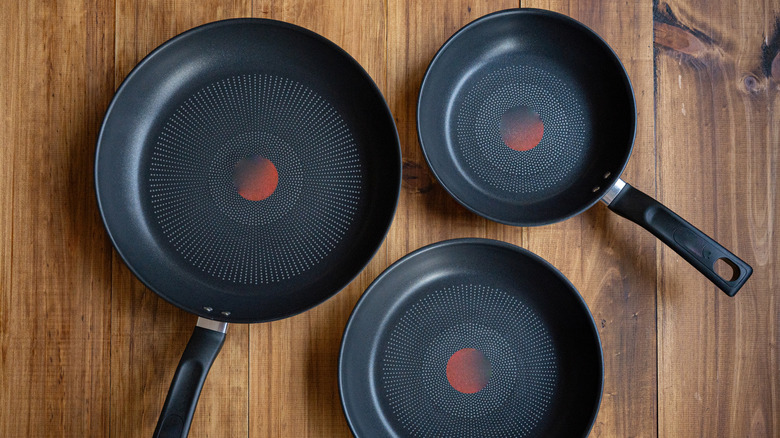 Nonstick frying pans on a wooden surface.