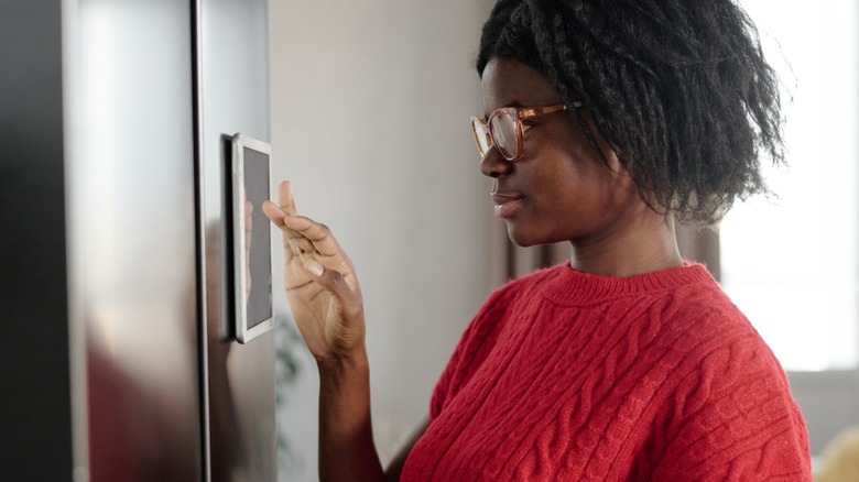A woman uses the display on a smart fridge.