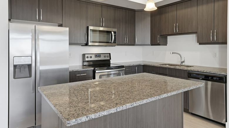 A clean and spacious kitchen with an island and granite countertops.