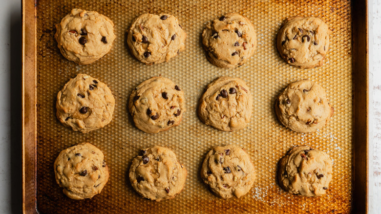 Chocolate chip cookies bake on an old, rust-colored sheet pan
