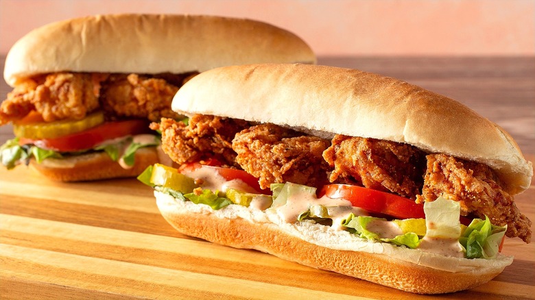 Two fried shrimp po' boy sandwiches on wooden board