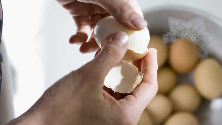 person peeling hard boiled egg