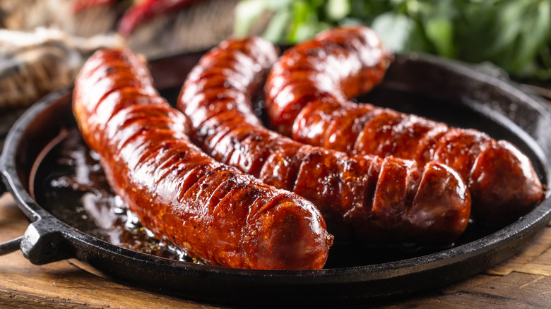 A semi-close-up image of three sausages, looking perfectly juicy with a slight char