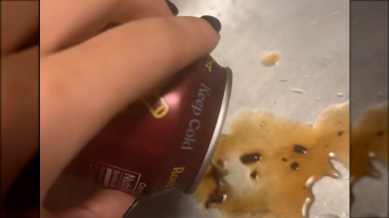 Dark clumps being poured out of  a can of Poppi