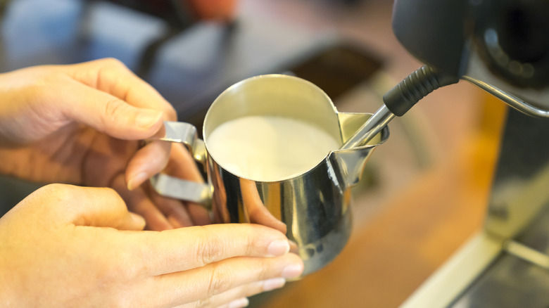 Two hands frothing milk for coffee