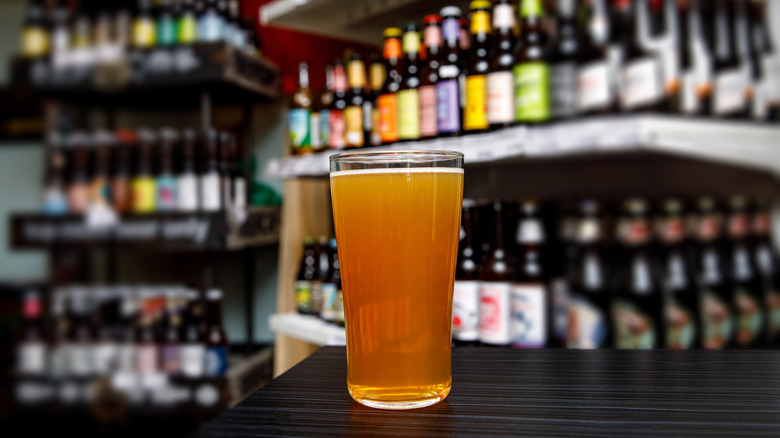 A pint of beer surrounded by bottles of beer