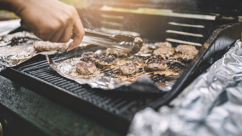 person grilling chicken over aluminum foil