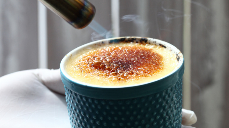 Crème brûlée getting its caramelized sugar crust with a kitchen torch.