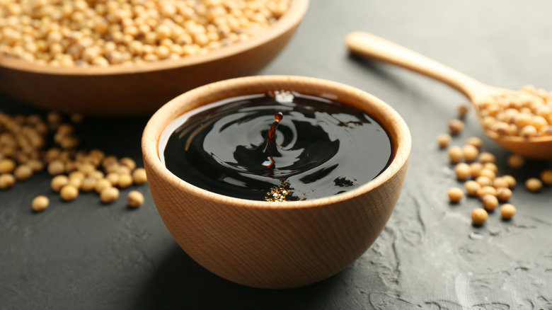 A bowl of soy sauce on a black table.