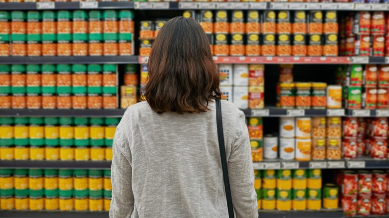 Woman standing in front of stacks of canned food