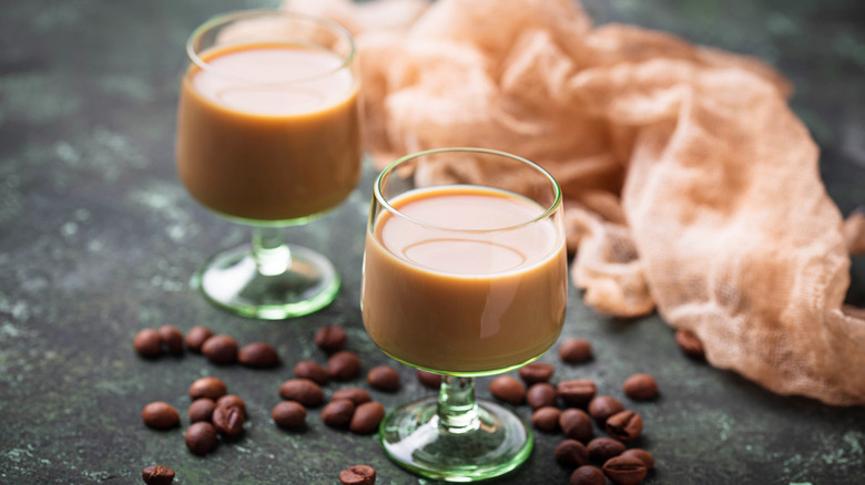 two shots of bailey's irish cream surrounded by coffee beans and a doily