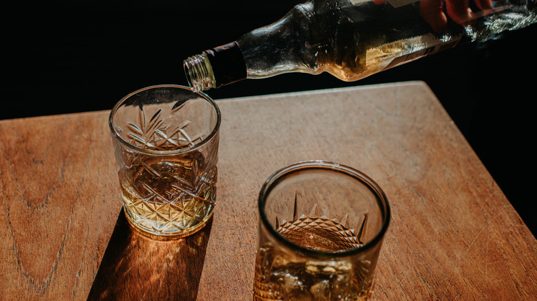 hand pouring bourbon into a glass