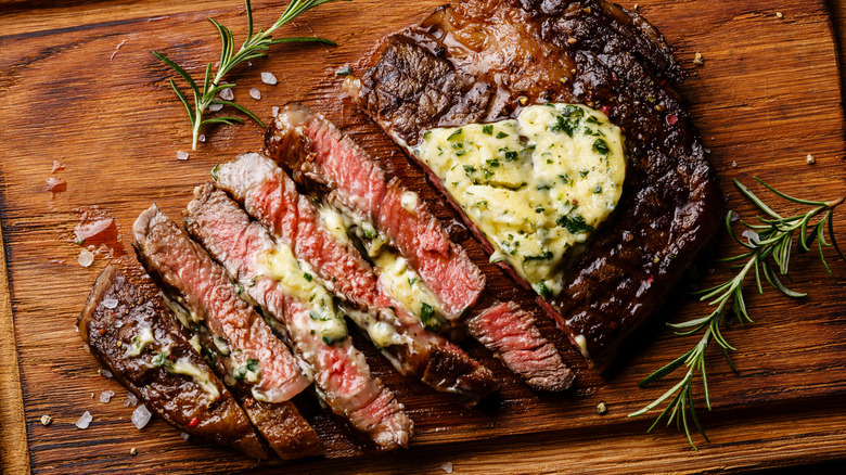 Grilled ribeye steak served with butter and herbs