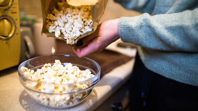 woman pouring microwave popcorn into bowl