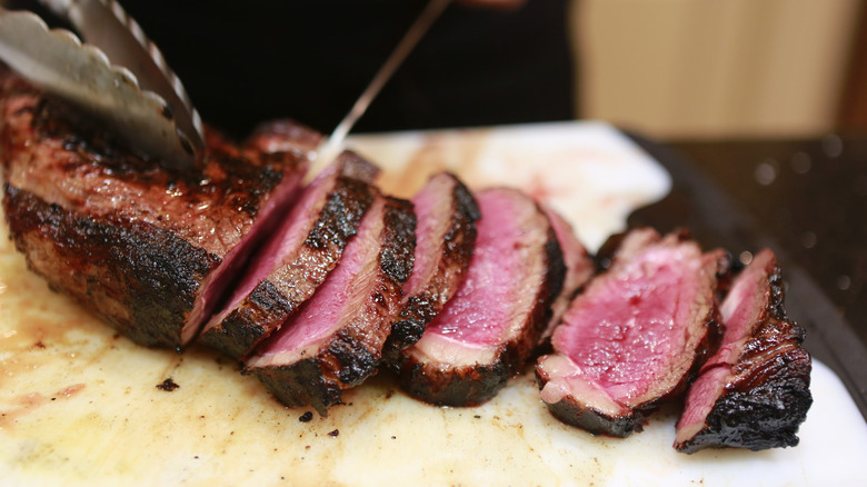 Knife slicing rare steak