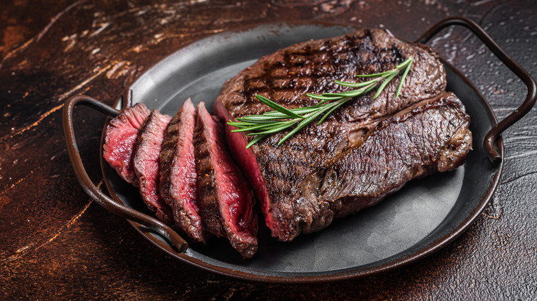 Seared top sirloin steak in pan with sprig of rosemary