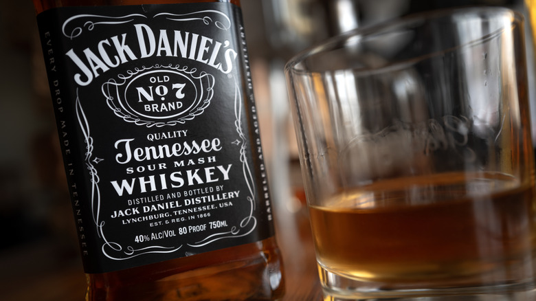 A closeup of a bottle of Jack Daniel's Tennessee whiskey and a glass with some clear brown liquid in it