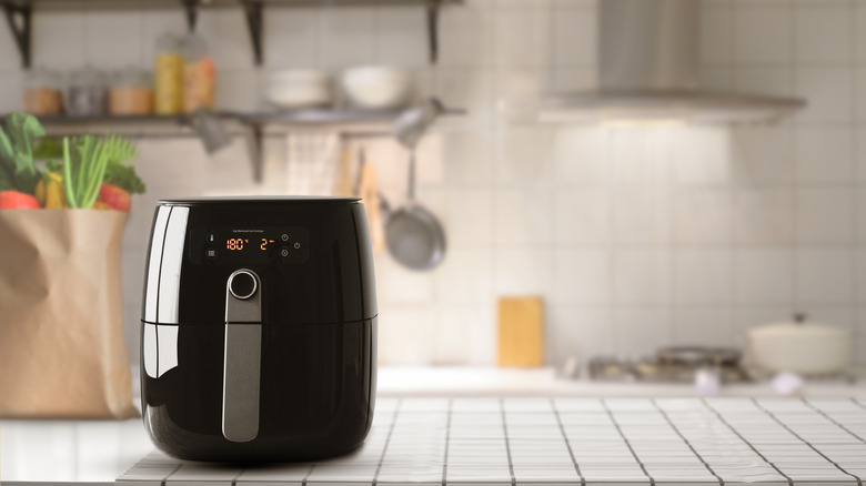 Black air fryer on a counter top in a white kitchen