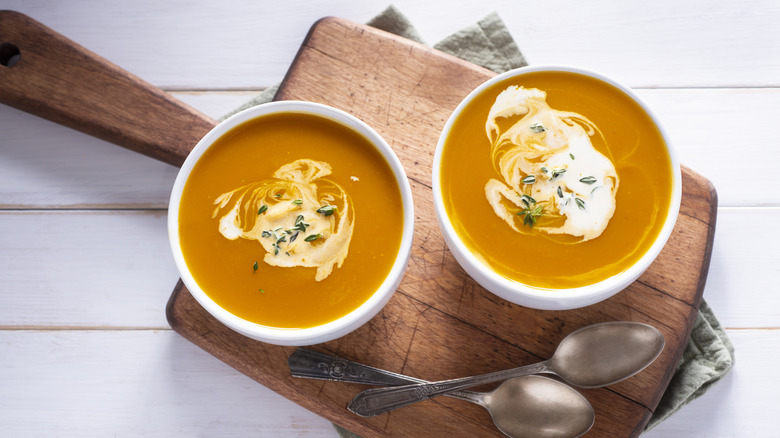 Two butternut squash soup bowls on a table.