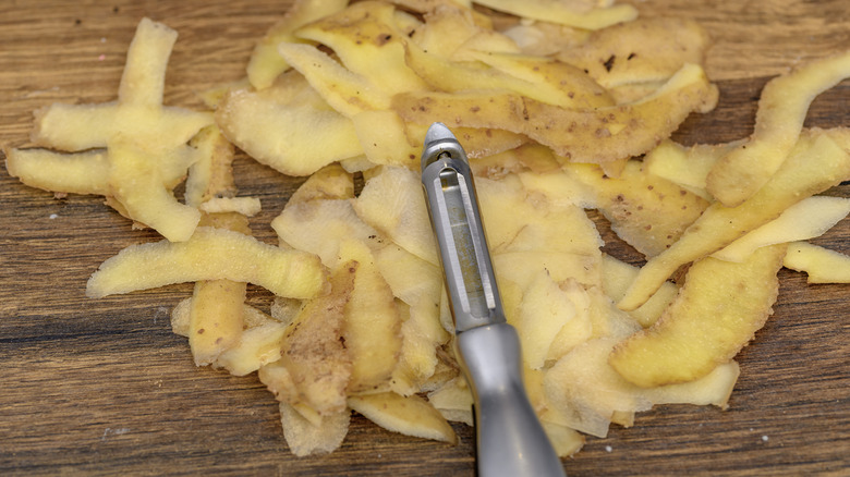 An illustrative image showing fresh potato peels scattered on a wooden surface.