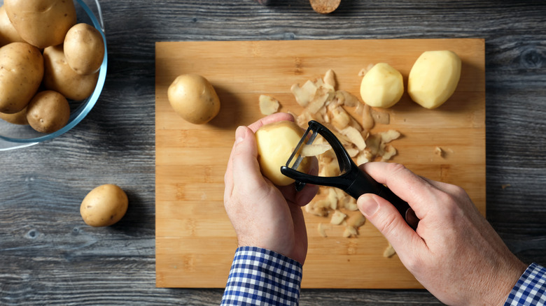 An illustrative image showing a person peeling a potato with a peeler