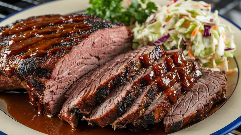 Smoked brisket topped with bbq sauce on a plate with coleslaw
