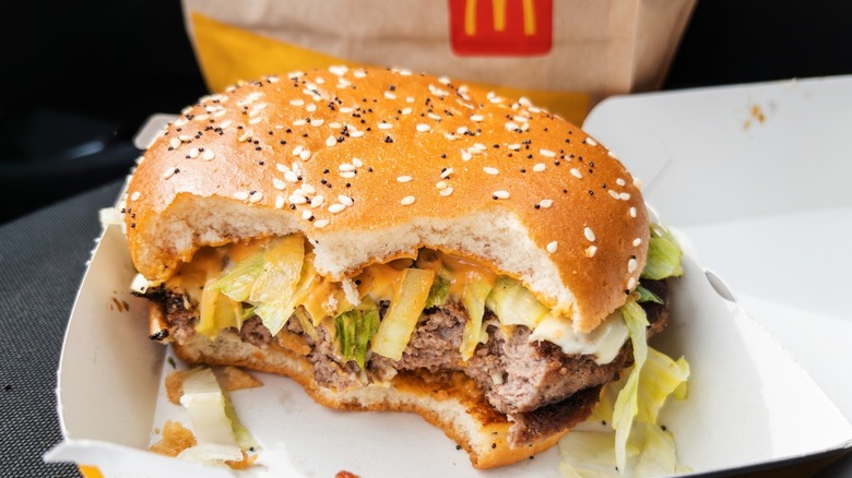 A half-eaten McDonalds burger sitting in the box it comes in