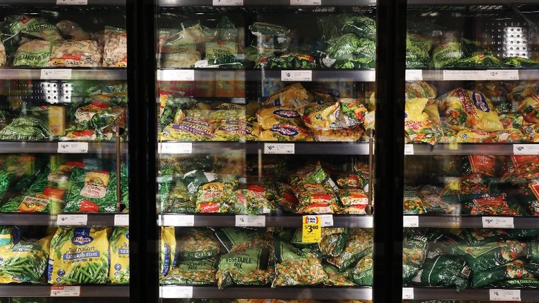 Birds Eye frozen vegetables and other brands sit in the freezer section of a grocery store.