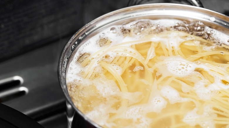 An iron pot filled with boiling spaghetti.