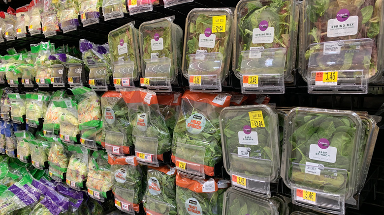 Packaged lettuce in clamshell containers and bags on the shelf at Walmart.