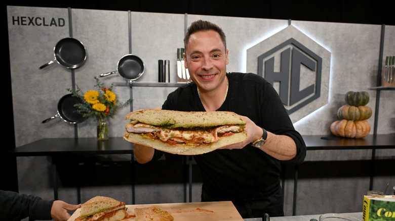 Jeff Mauro poses holding a sandwich