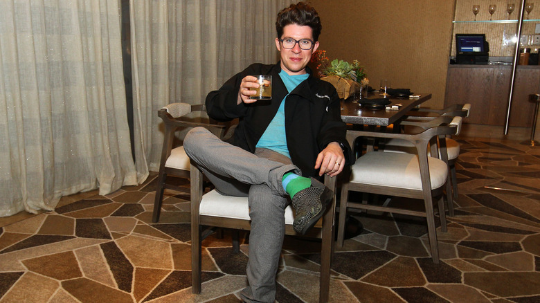 Justin Warner poses with drink while sitting in chair