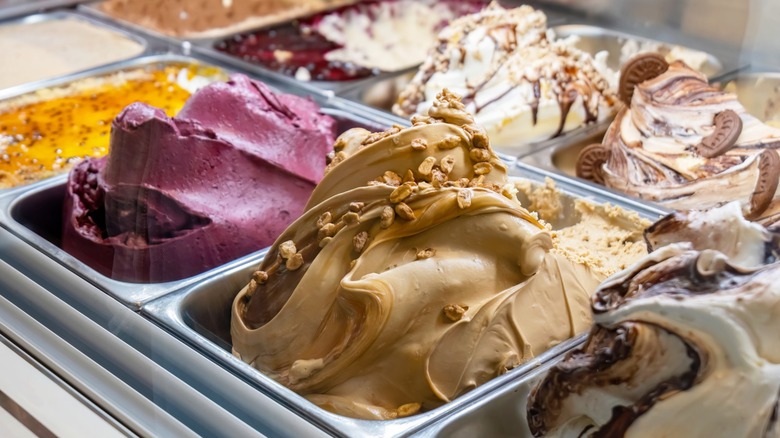 Tubs of freshly-made ice cream behind a counter at an ice cream shop.