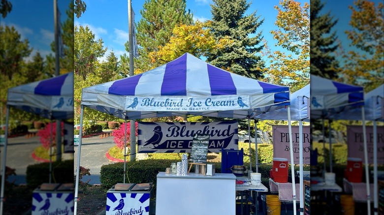Bluebird Ice Cream stand at a farmers market on a bright day