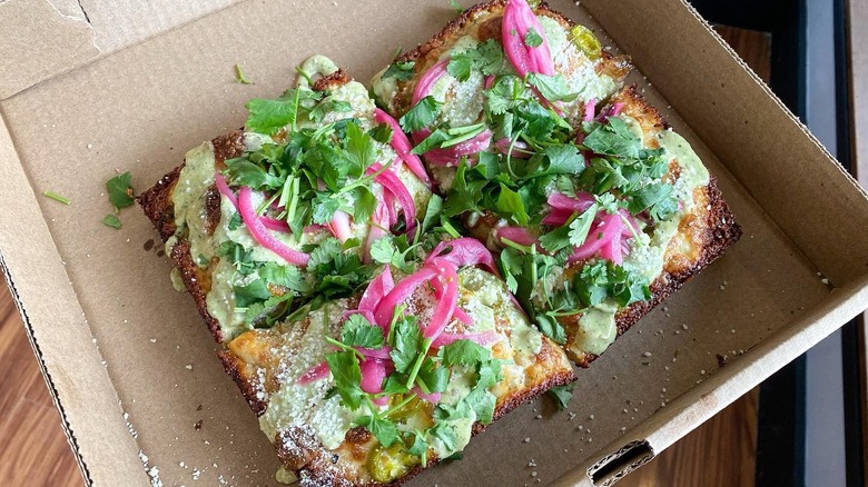 A slice Viva Mexico Detroit-style pizza in a takeaway box from Jay's Artisan Pizza