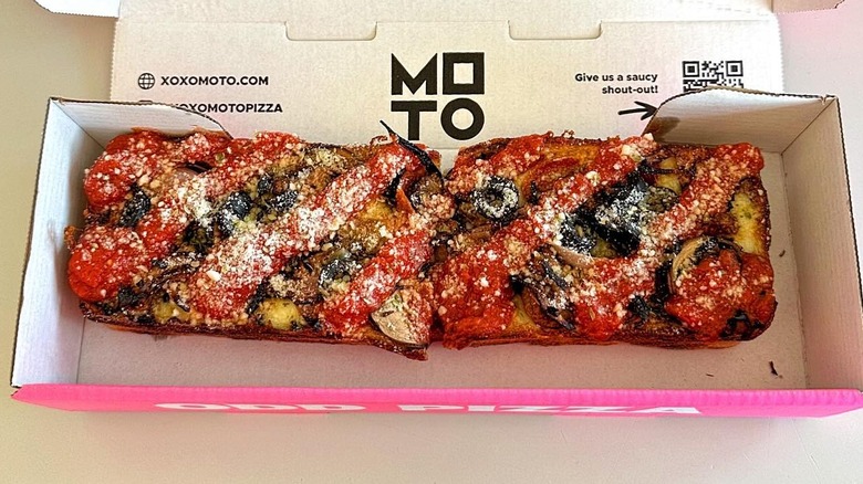 A slice of MOTO Pizza in a takeaway box