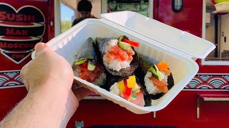 A person holding a container of sushi rolls at the Moscow Farmers Market in Moscow