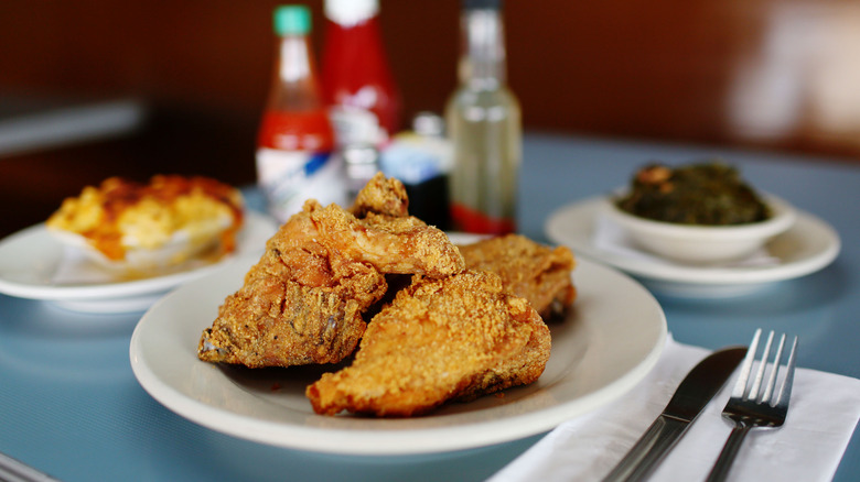 A plate of fried chicken served with collard greens and mac and cheese