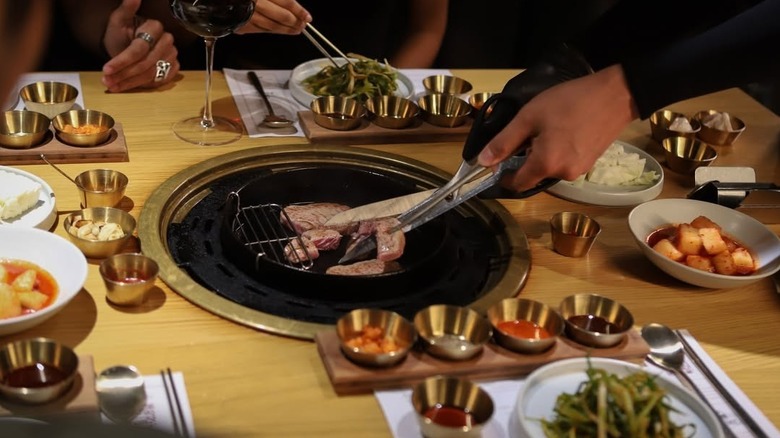 A person cutting up a steak over a grill